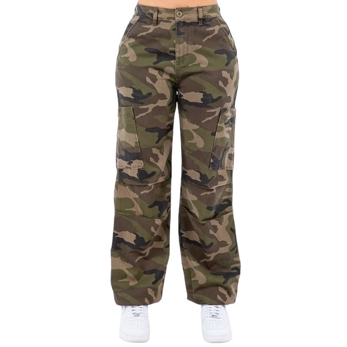 a woman wearing camouflage pants and white sneakers