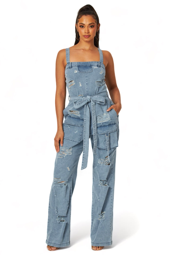 a woman wearing a denim jumpsuit with a tie around the waist