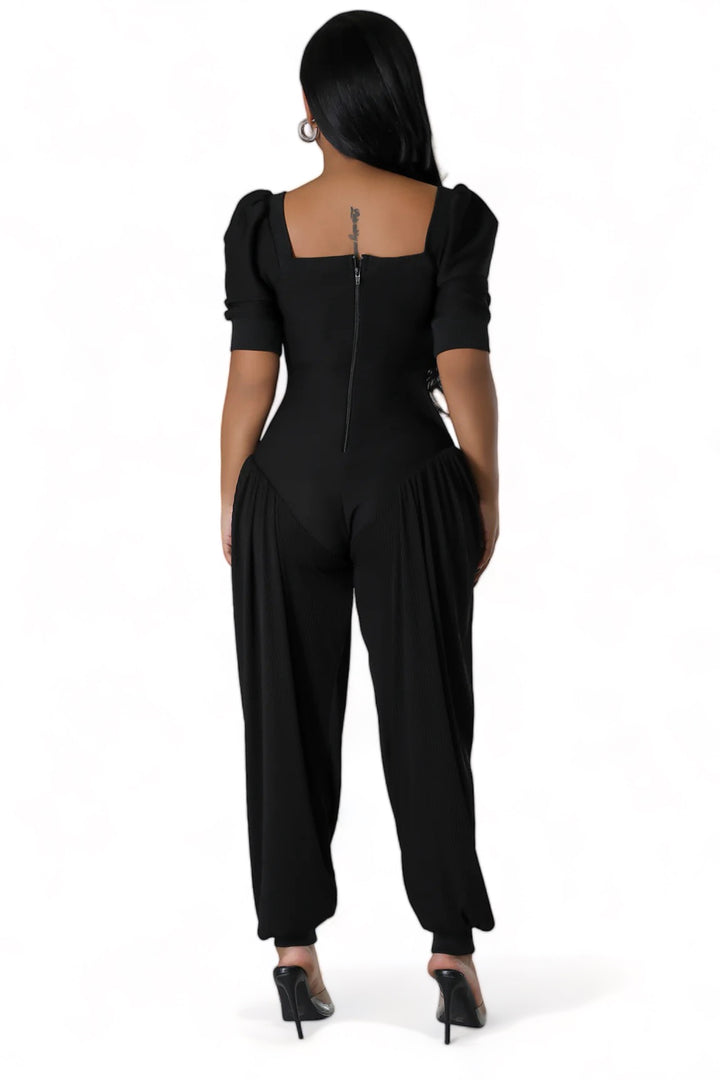 a woman wearing a black jumpsuit and heels