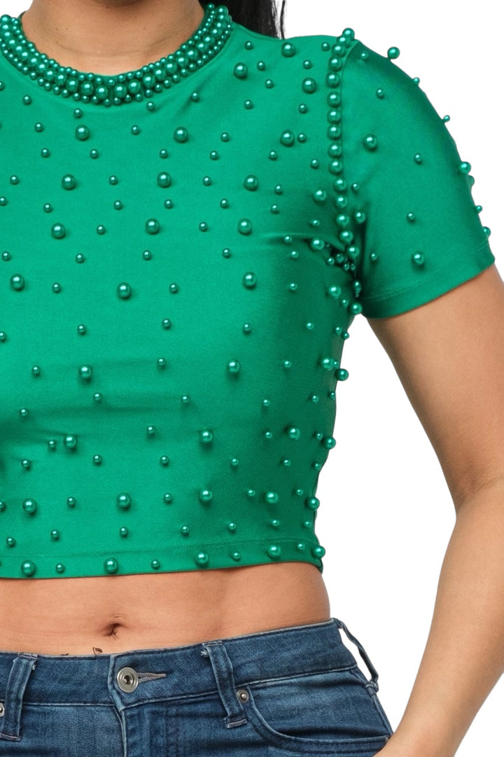 a woman wearing a green top with pearls on it