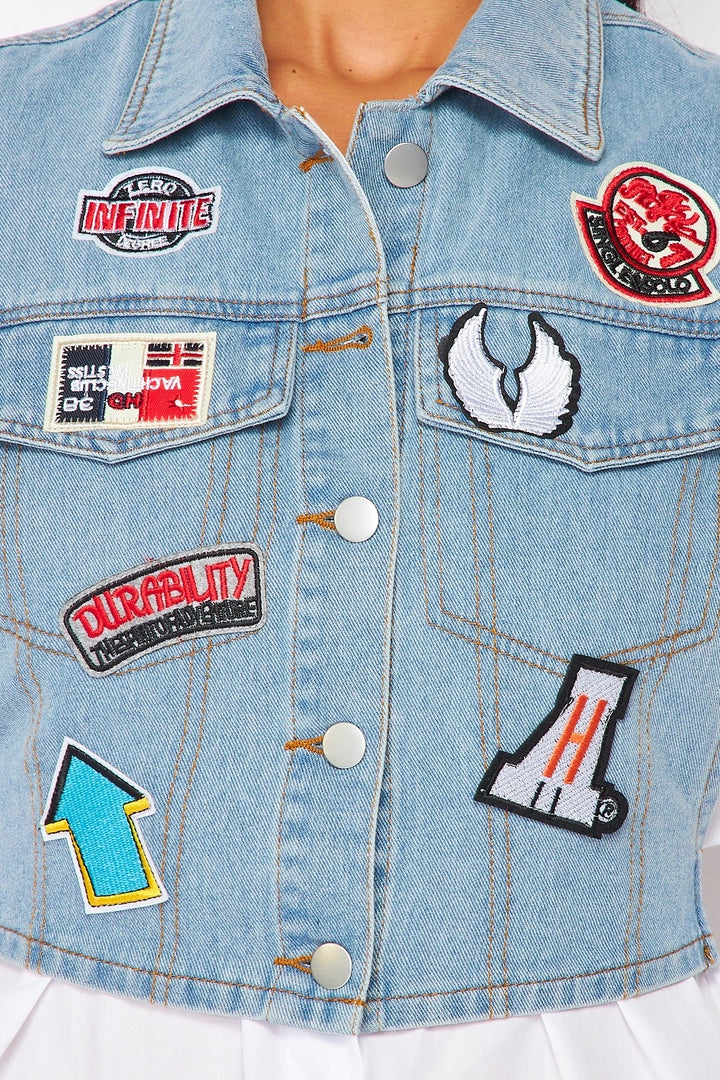 a woman wearing a jean jacket with patches on it