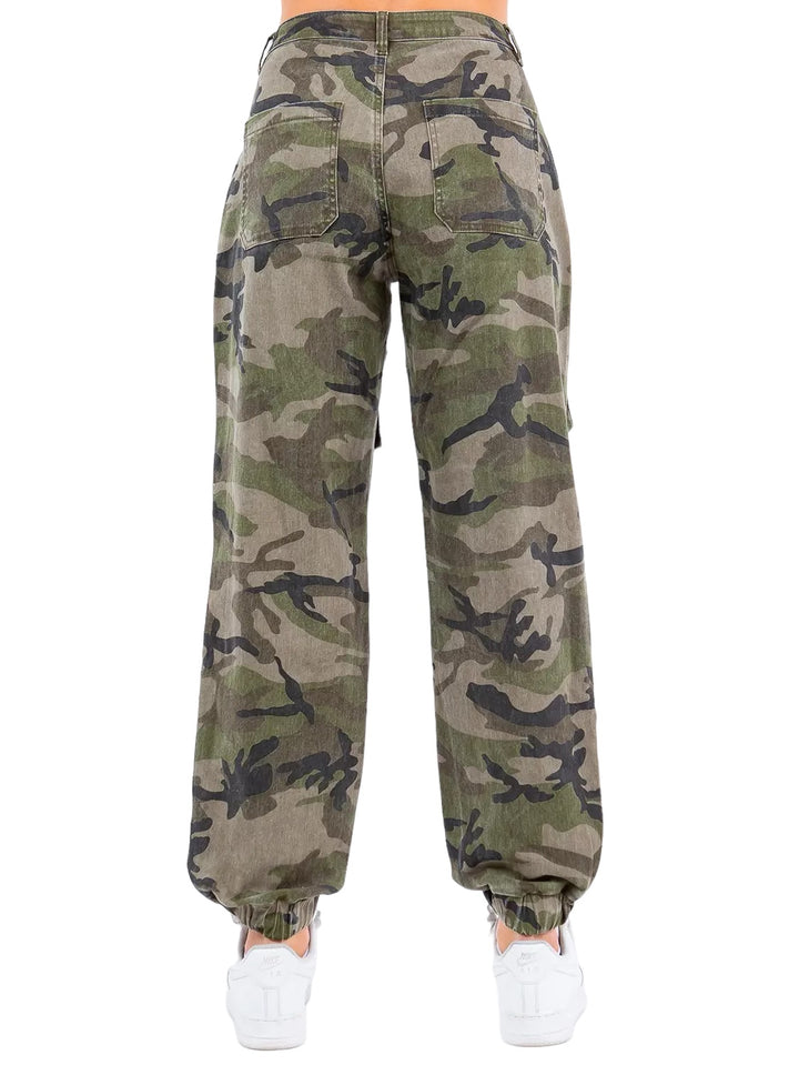 a woman wearing camouflage pants and white sneakers