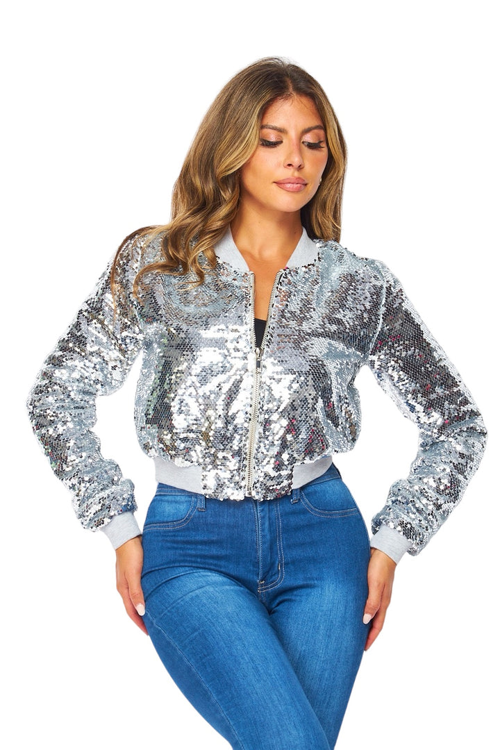 a woman wearing a silver jacket and jeans