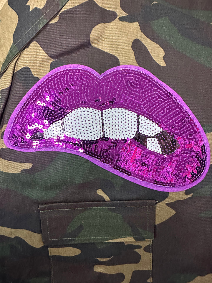 a purple sequin lip on a camouflage jacket