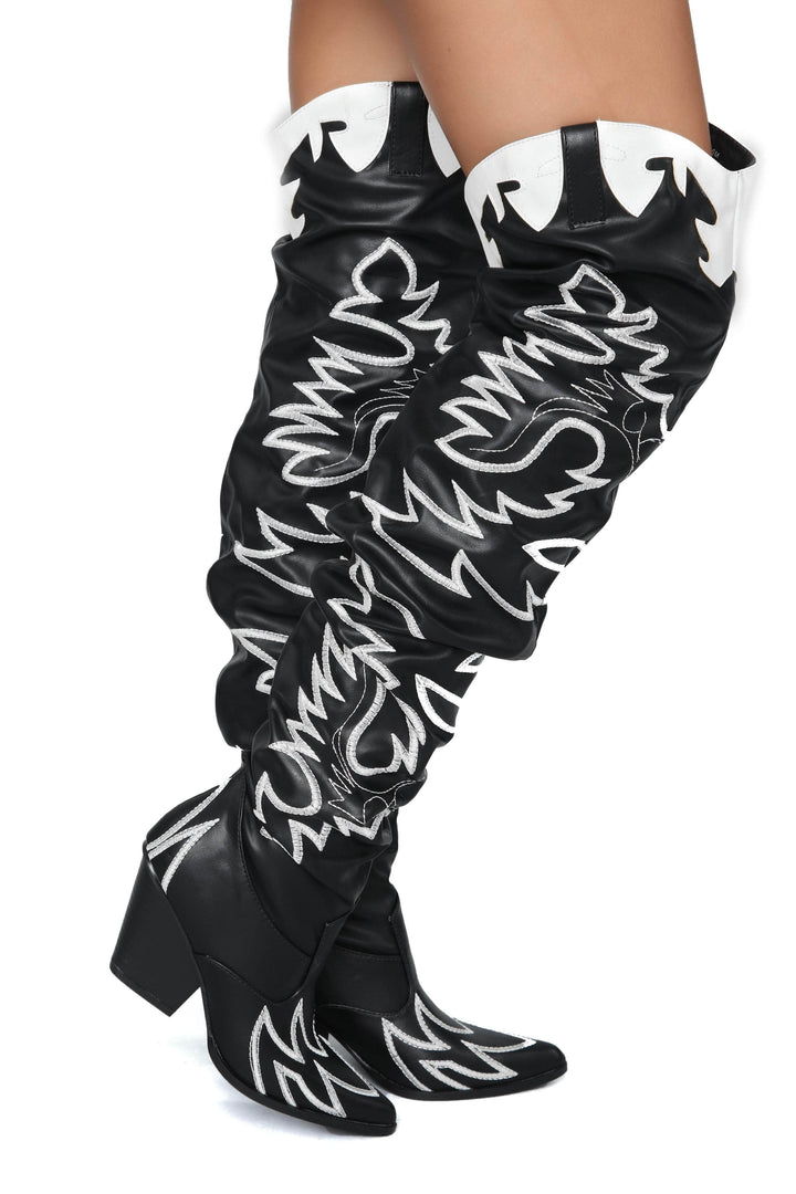 a woman wearing black and white knee high boots