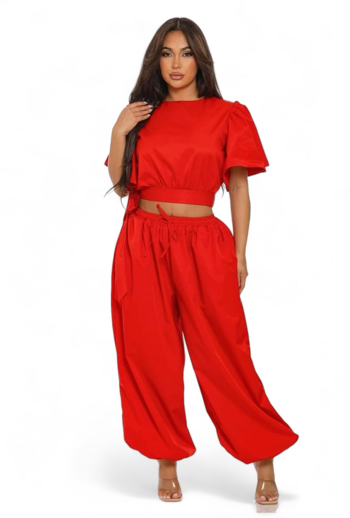 a woman wearing a red crop top and wide legged pants