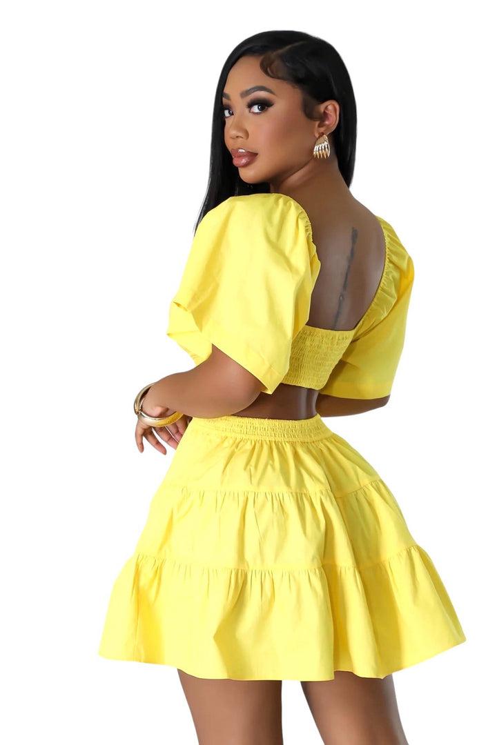 a woman in a yellow dress with her hands on her hips