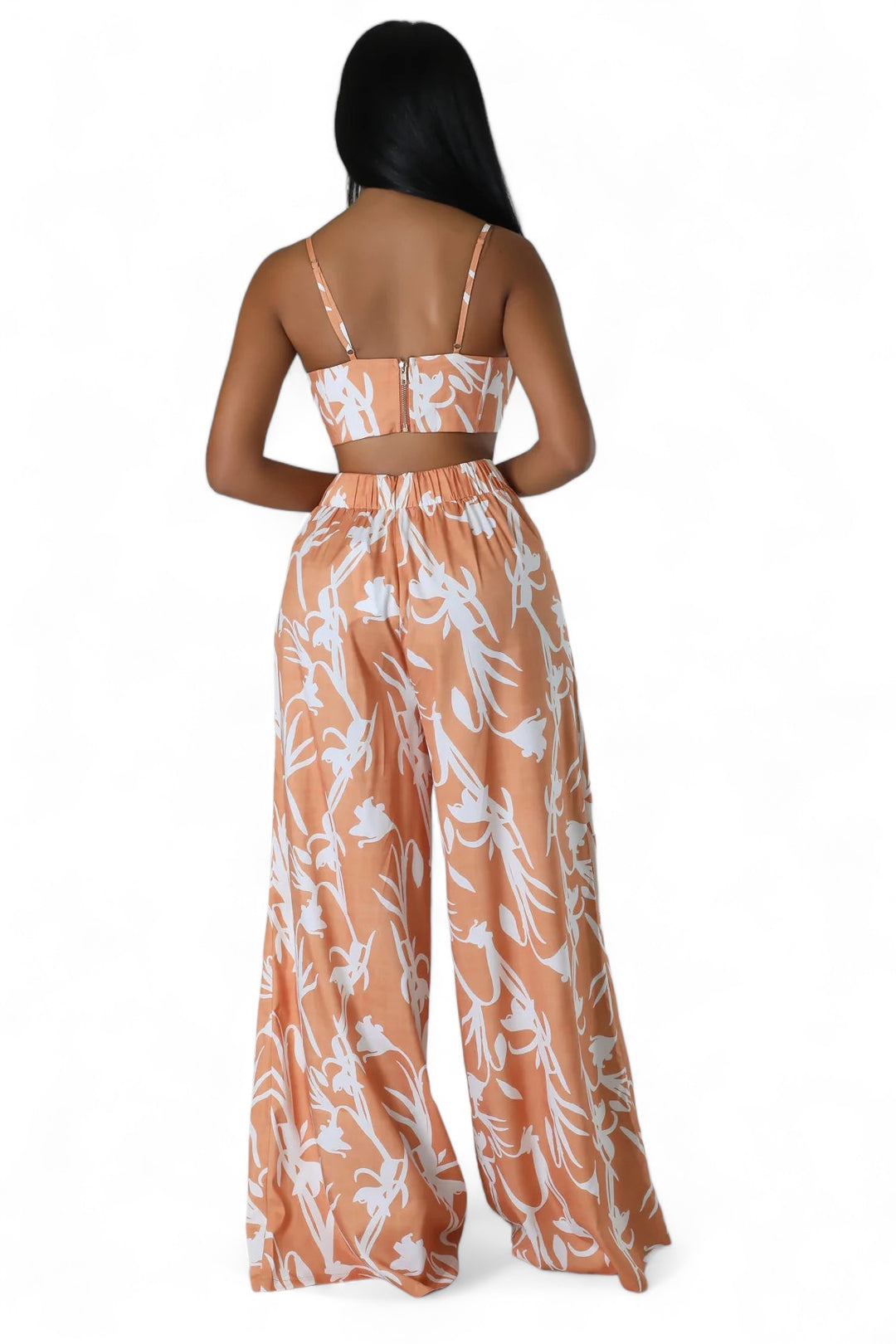 a woman wearing an orange and white floral print jumpsuit