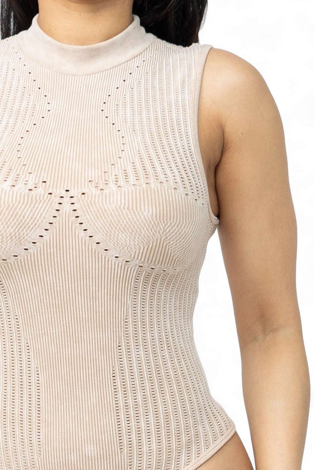 a woman wearing a tan bodysuit with holes on it