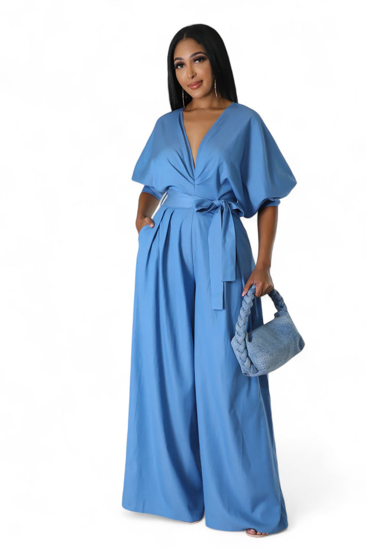a woman wearing a blue jumpsuit and a purse