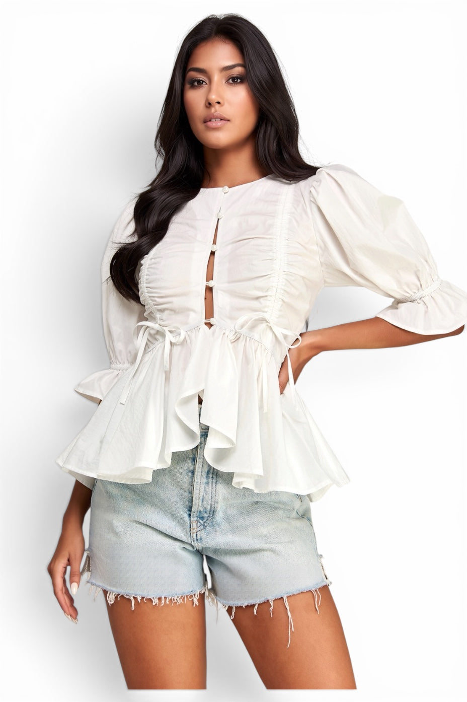 Women's white ruched peplum blouse with front button detail, puff sleeves, ruffle hem, and feminine flowy silhouette styled with denim shorts.