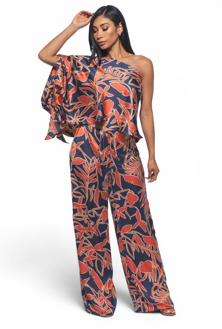 Women's tropical print satin matching set with one-shoulder flowy top and wide leg pants, resort-inspired statement outfit.