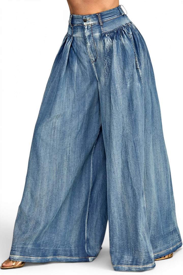 Medium wash high-rise denim palazzo jeans featuring elegant front pleats, an ultra-wide leg silhouette, and a relaxed flowing fit.
