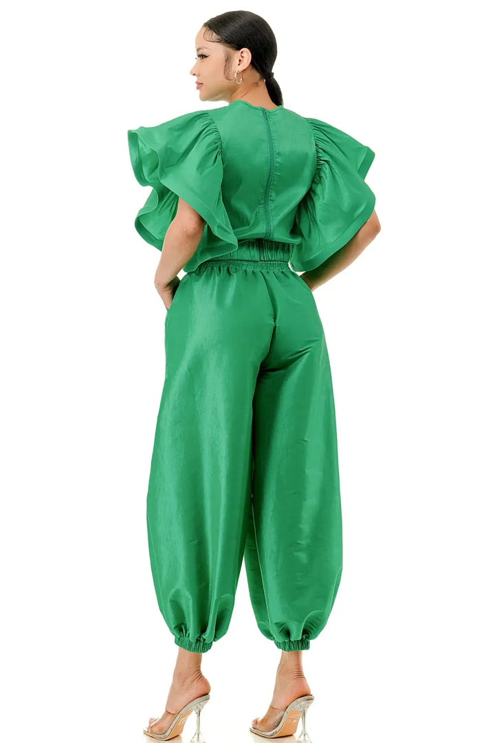 a woman wearing a green jumpsuit and heels