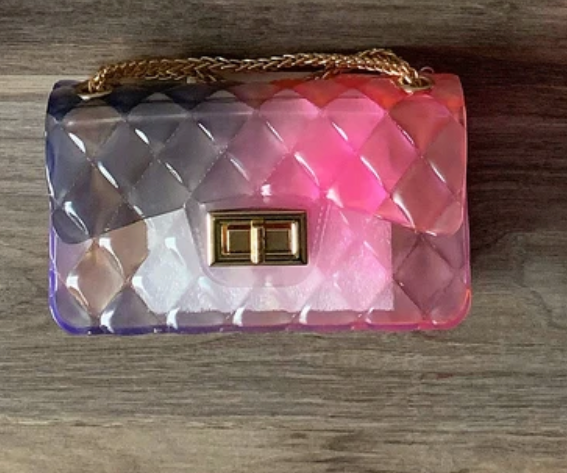a pink and purple purse sitting on top of a wooden table